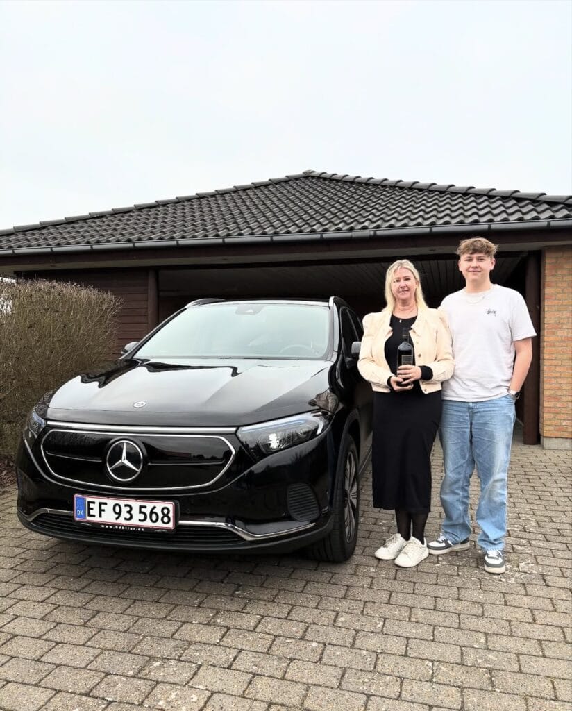 To personer står foran sort Mercedes ved hus