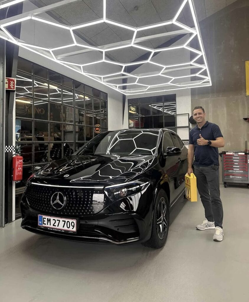 Mand står ved sort Mercedes i moderne garage