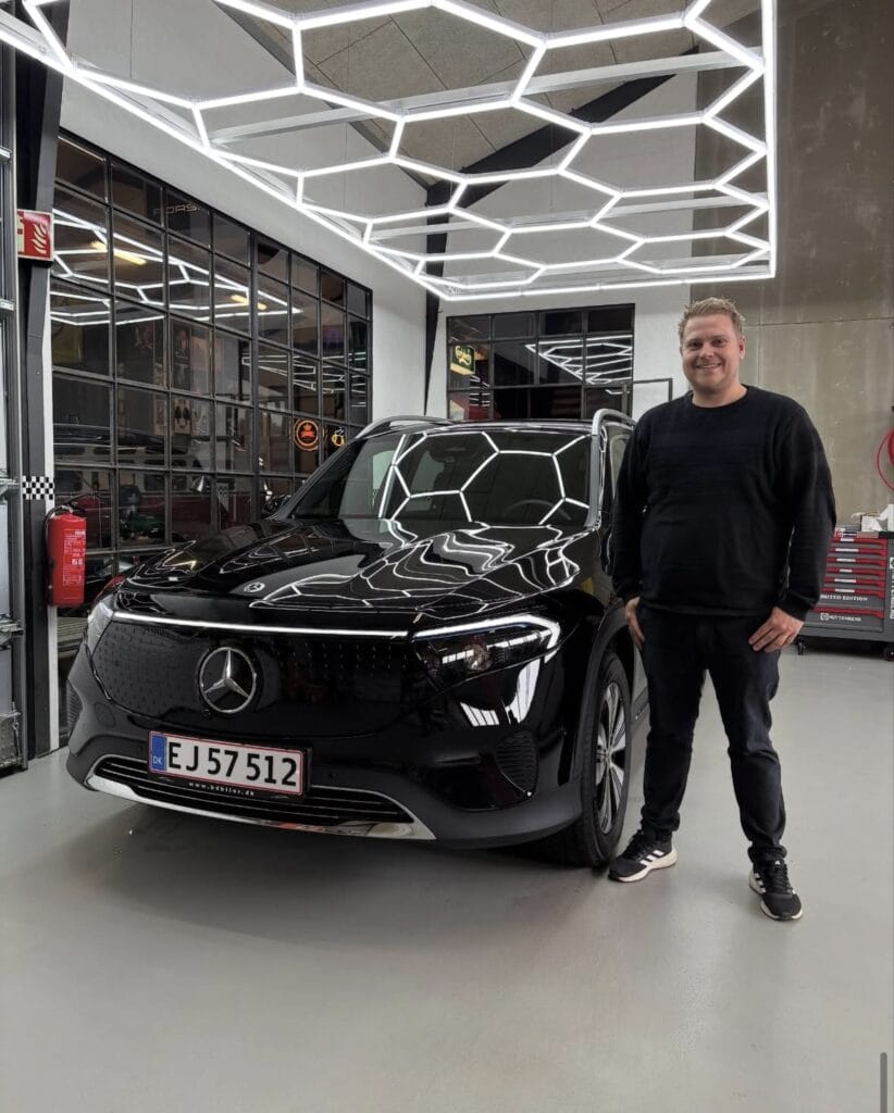 Mand står ved sort Mercedes i garage